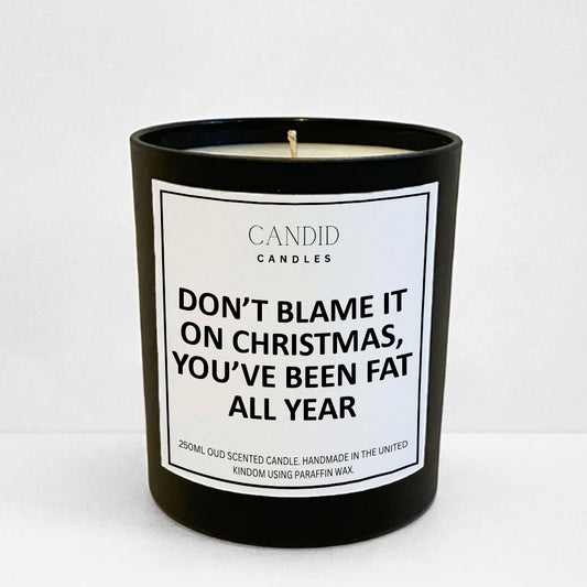 Festive offensive candle with white label "Don't Blame It On Christmas, You've Been Fat All Year" on jar