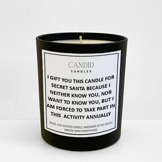 Funny candle with white label "Forced Secret Santa Present" printed on jar